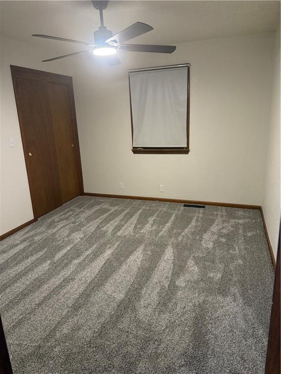 unfurnished bedroom with a closet, carpet flooring, ceiling fan, and baseboards