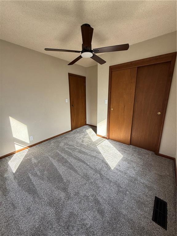 unfurnished bedroom with visible vents, baseboards, carpet floors, a textured ceiling, and a ceiling fan