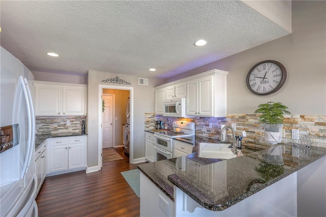 21212 E 52nd Street Ct, Blue Springs, MO 64015 - kitchen featuring visible vents, a sink, white appliances, a peninsula, and washer / clothes dryer