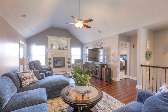 21212 E 52nd Street Ct, Blue Springs, MO 64015 - living room featuring dark wood finished floors, a tiled fireplace, baseboards, vaulted ceiling, and a ceiling fan