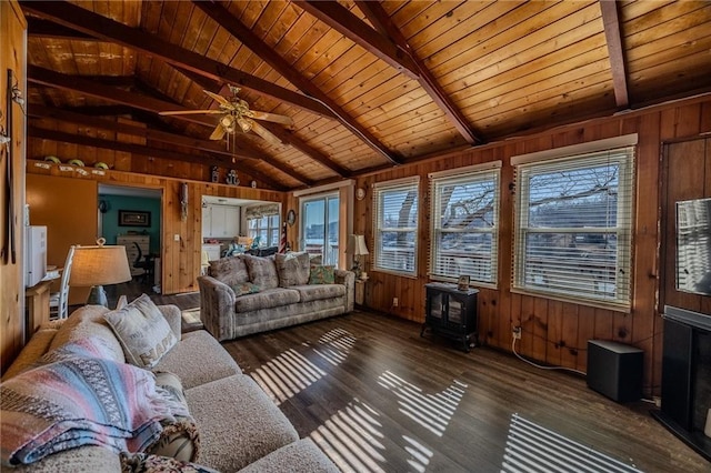 living area featuring wooden walls, vaulted ceiling with beams, wood finished floors, and a wood stove