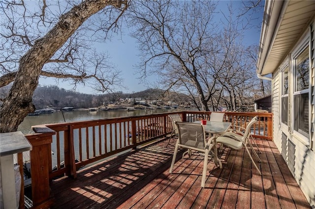 wooden terrace featuring outdoor dining area and a water view