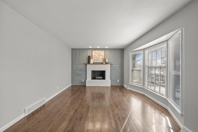 unfurnished living room featuring wood finished floors, visible vents, baseboards, recessed lighting, and a brick fireplace