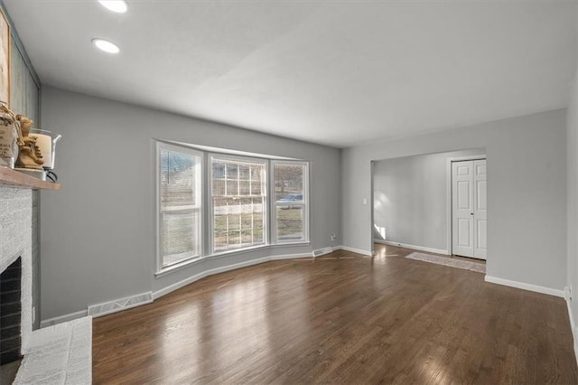 unfurnished living room with visible vents, baseboards, dark wood-style flooring, and a fireplace