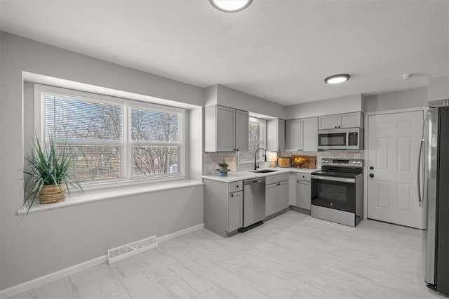 kitchen with a sink, stainless steel appliances, gray cabinetry, and visible vents