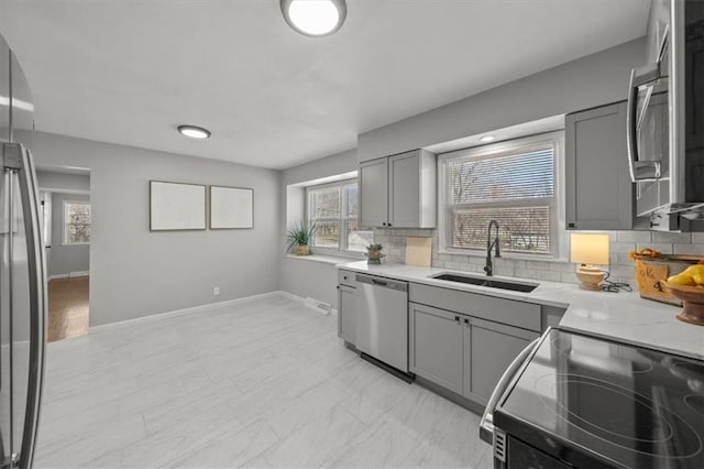 kitchen with gray cabinets, stainless steel appliances, and a sink