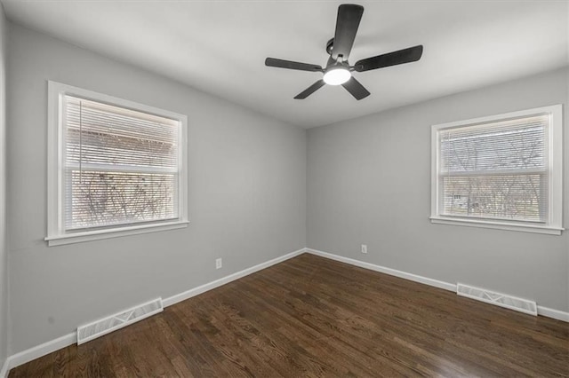 spare room with visible vents, baseboards, a ceiling fan, and dark wood-style flooring