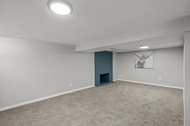 finished below grade area with baseboards, a large fireplace, and carpet