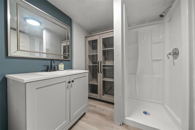 bathroom with vanity, wood finished floors, and a stall shower