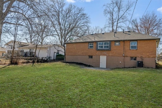 rear view of house with fence, a yard, central AC unit, and brick siding