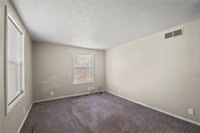 carpeted spare room featuring visible vents, a textured ceiling, and baseboards