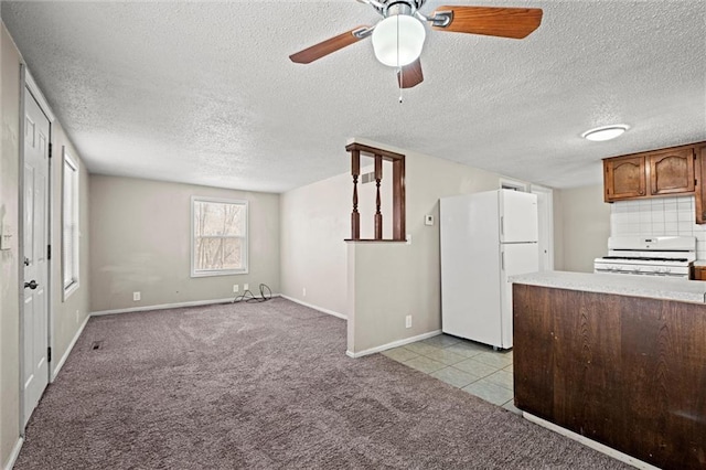 kitchen with backsplash, light colored carpet, light countertops, white appliances, and a ceiling fan