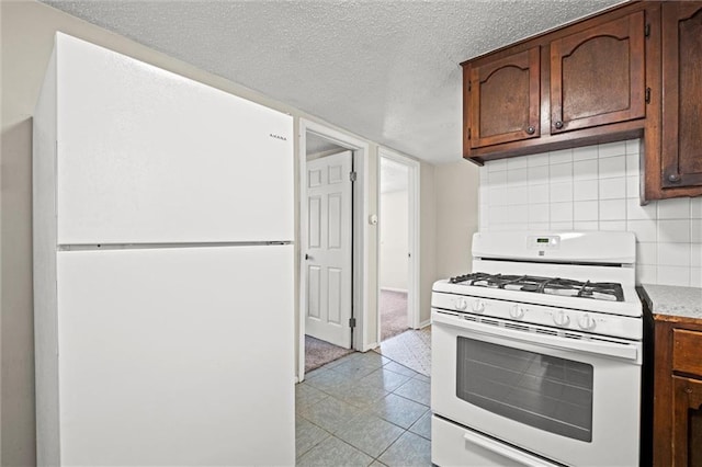 kitchen featuring a textured ceiling, white appliances, light countertops, light tile patterned floors, and decorative backsplash