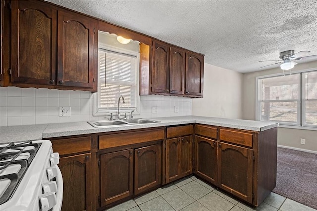 kitchen with ceiling fan, light colored carpet, light countertops, a peninsula, and a sink