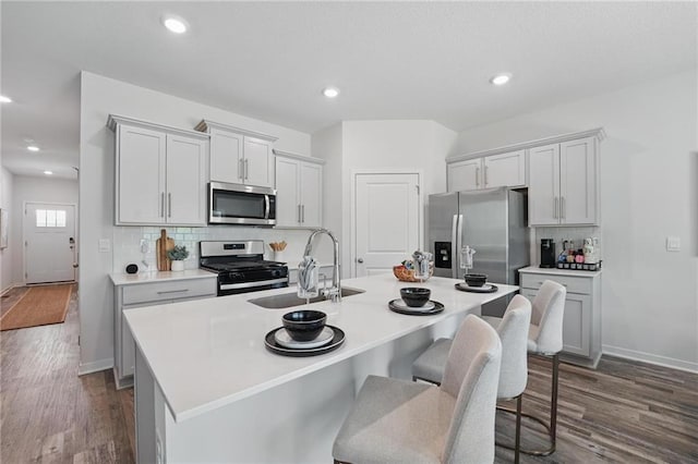 1605 Maci St, Belton, MO 64012 - kitchen featuring stainless steel appliances, a sink, dark wood-type flooring, a center island with sink, and recessed lighting