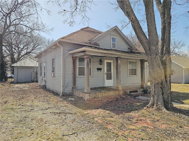 bungalow-style home with cooling unit, an outbuilding, and covered porch