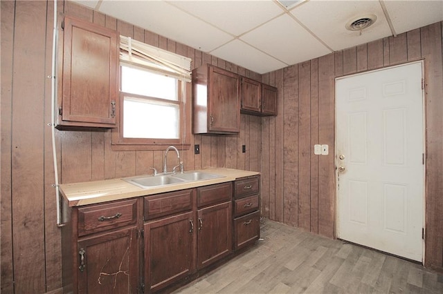 kitchen featuring a sink, wooden walls, and light wood finished floors