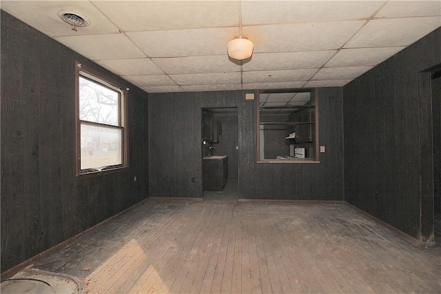 empty room featuring visible vents, a sink, a paneled ceiling, and hardwood / wood-style floors