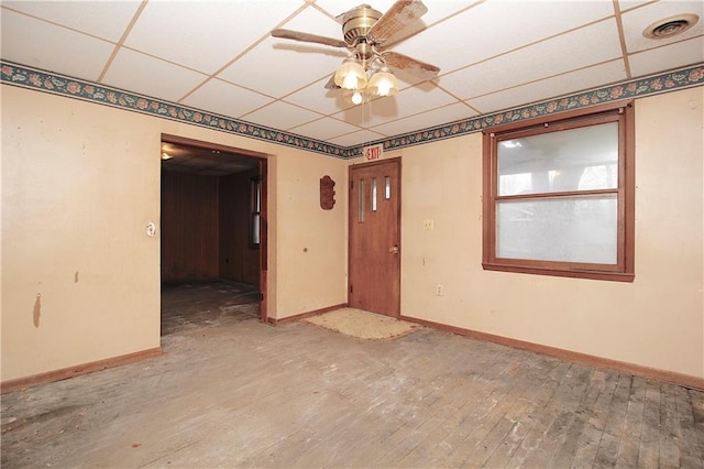 spare room with a ceiling fan, hardwood / wood-style flooring, a paneled ceiling, and baseboards