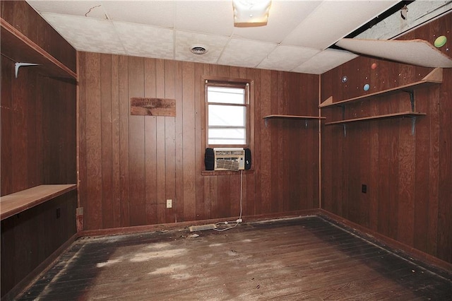 empty room featuring wooden walls, cooling unit, wood finished floors, and visible vents