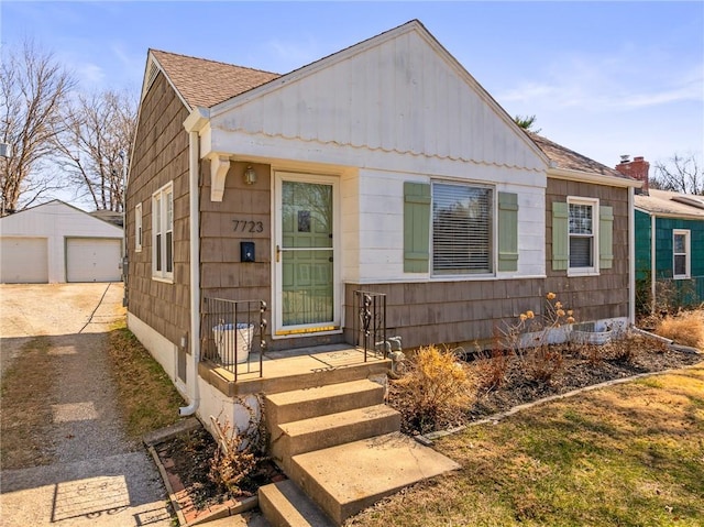 view of front of home with a detached garage, an outdoor structure, and roof with shingles