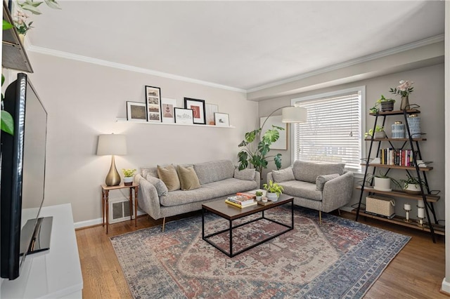 living room featuring visible vents, baseboards, wood finished floors, and crown molding