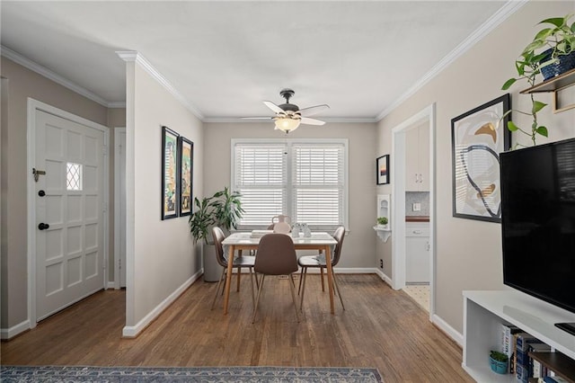 dining room featuring ornamental molding, a ceiling fan, baseboards, and wood finished floors