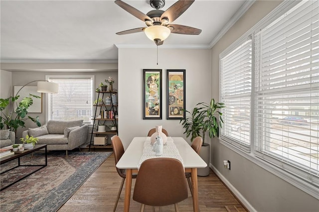 dining room featuring a ceiling fan, crown molding, wood finished floors, and baseboards