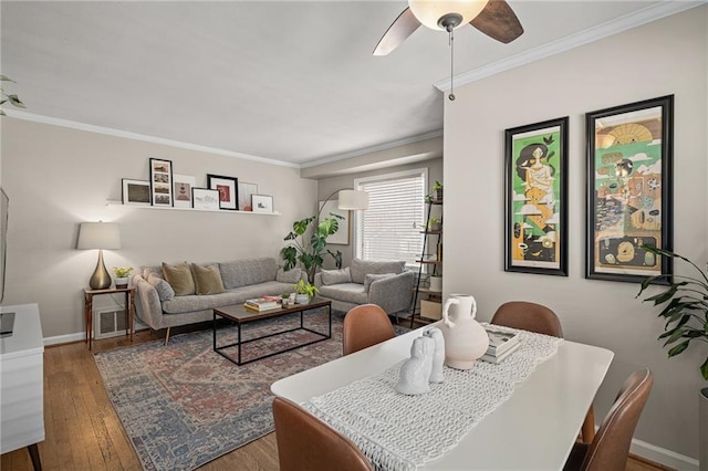 living area featuring baseboards, crown molding, ceiling fan, and wood finished floors