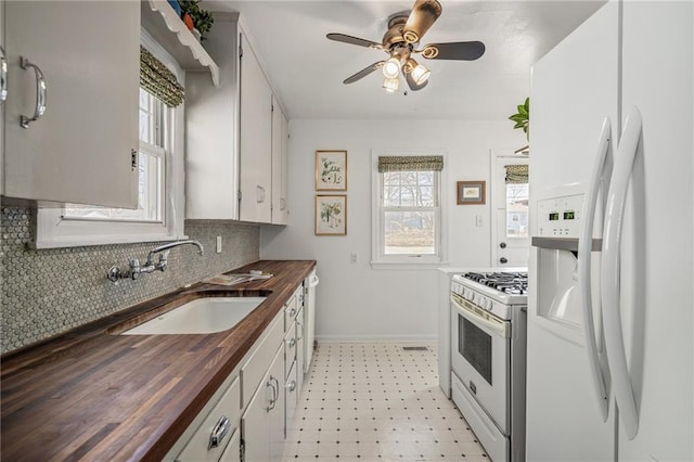 kitchen with wooden counters, light floors, white appliances, a ceiling fan, and a sink