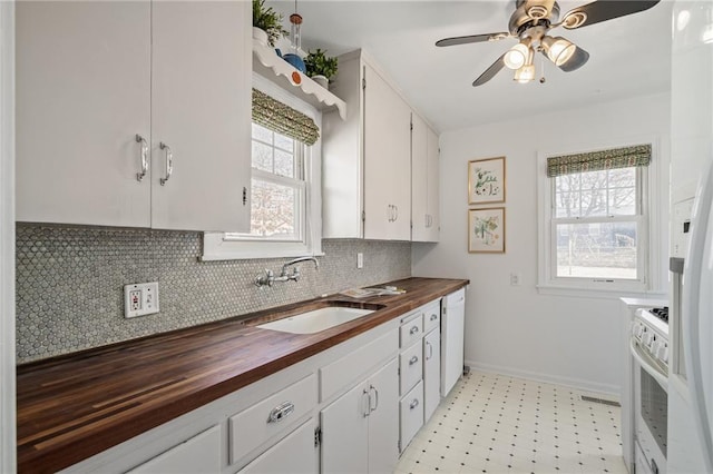 kitchen with a sink, backsplash, white appliances, wooden counters, and ceiling fan