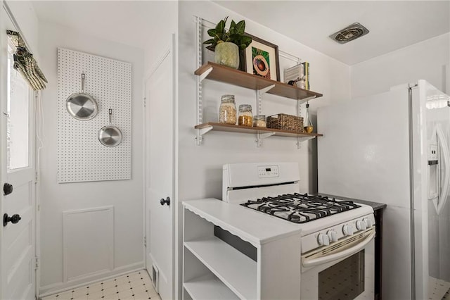 kitchen featuring open shelves, white appliances, and light floors