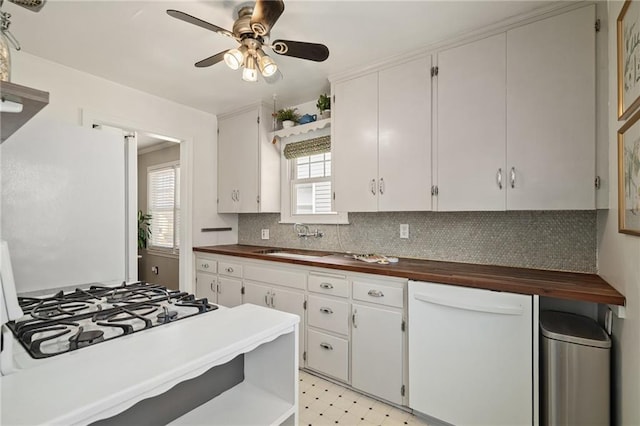 kitchen featuring light floors, decorative backsplash, white dishwasher, a ceiling fan, and a sink