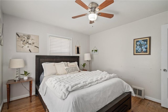 bedroom with ceiling fan, visible vents, baseboards, and wood finished floors