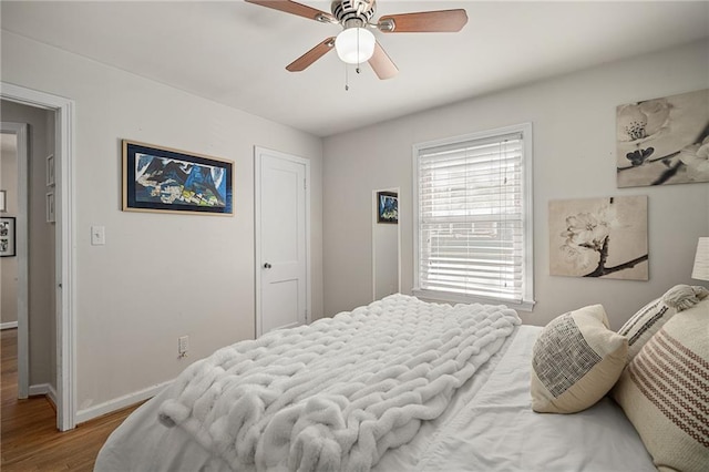 bedroom with a ceiling fan, baseboards, and wood finished floors