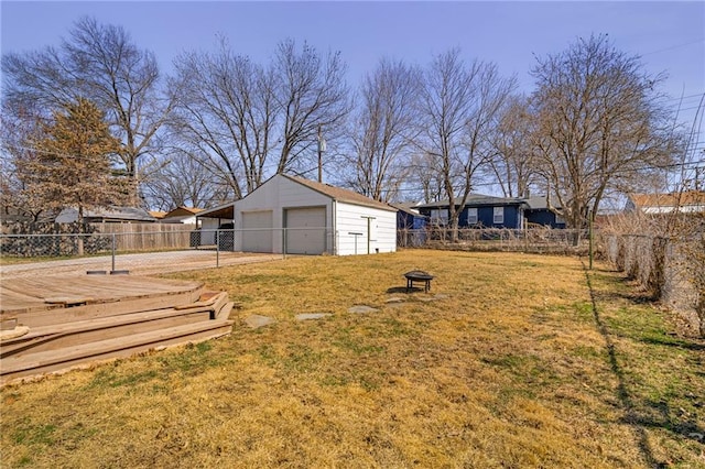 view of yard with a detached garage, fence, and an outbuilding