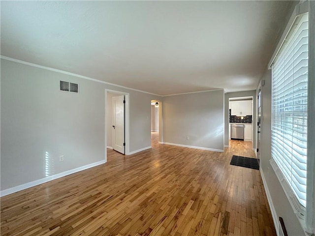 spare room with visible vents, baseboards, light wood-style floors, and crown molding