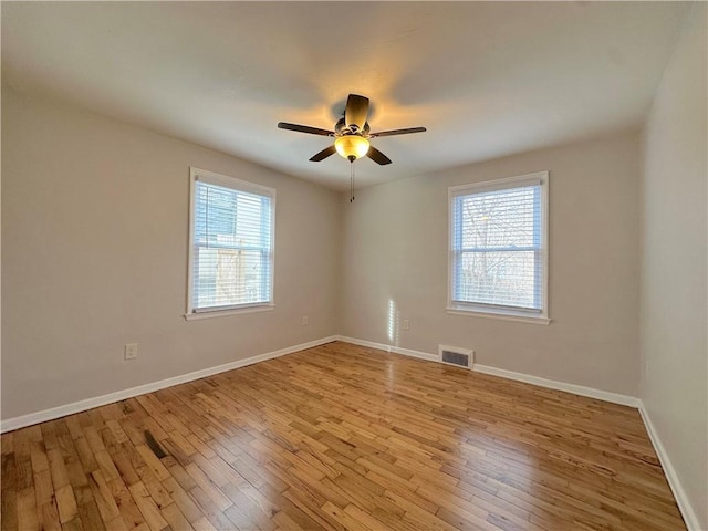 spare room with a wealth of natural light, visible vents, and hardwood / wood-style floors