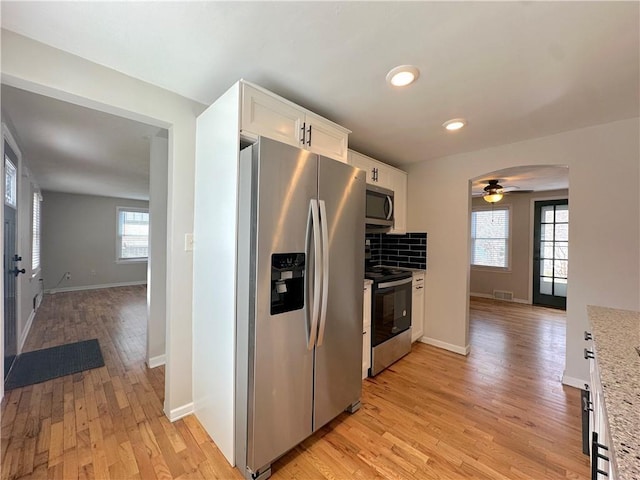 kitchen with visible vents, light wood finished floors, stainless steel appliances, decorative backsplash, and white cabinets