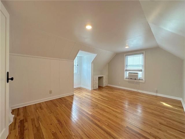 bonus room with light wood-style flooring, cooling unit, baseboards, and vaulted ceiling