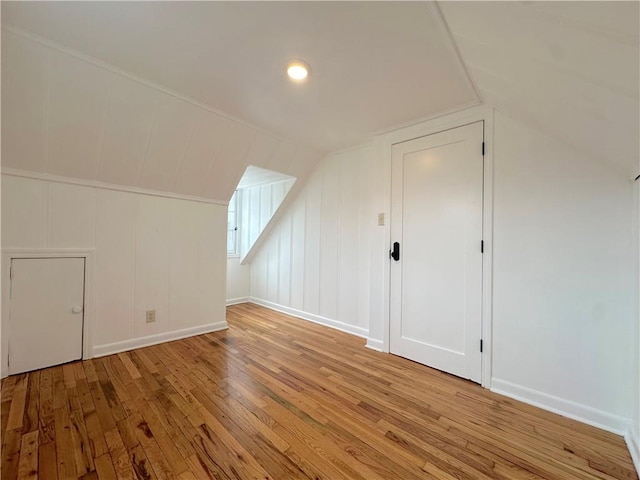 additional living space featuring light wood-style flooring, baseboards, and lofted ceiling