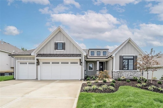 view of front of house with a front yard, roof with shingles, concrete driveway, a garage, and board and batten siding