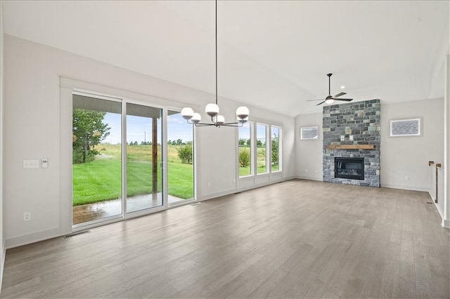 unfurnished living room featuring wood finished floors, visible vents, lofted ceiling, a fireplace, and ceiling fan with notable chandelier