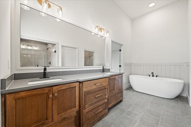 bathroom featuring a sink, tiled shower, wainscoting, and double vanity