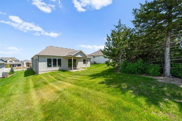 rear view of house featuring a lawn and central AC unit