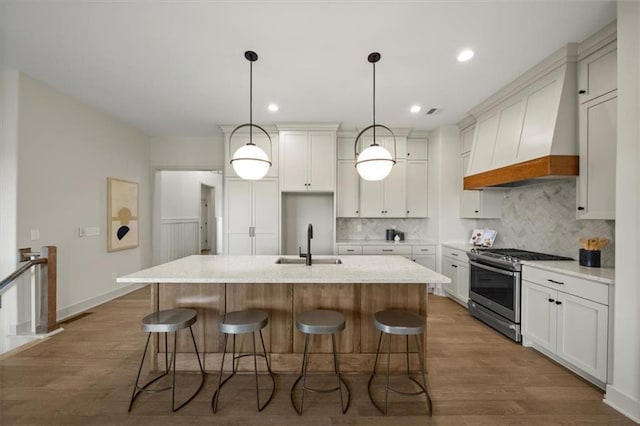22109 W 80th Ter, Shawnee, KS 66220 - kitchen featuring gas range, custom range hood, wood finished floors, tasteful backsplash, and a center island with sink
