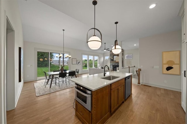 22109 W 80th Ter, Shawnee, KS 66220 - kitchen with a fireplace, brown cabinetry, stainless steel appliances, a chandelier, and a kitchen island with sink