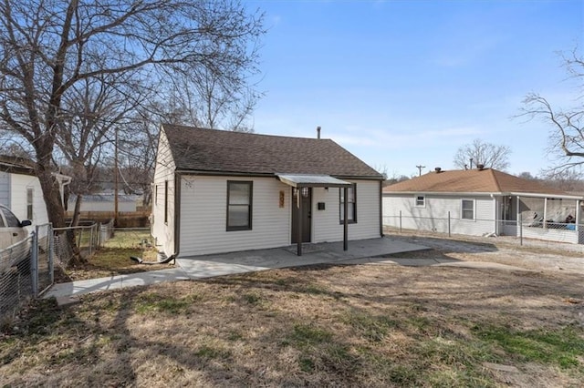 bungalow featuring a patio, a sunroom, a fenced backyard, and roof with shingles