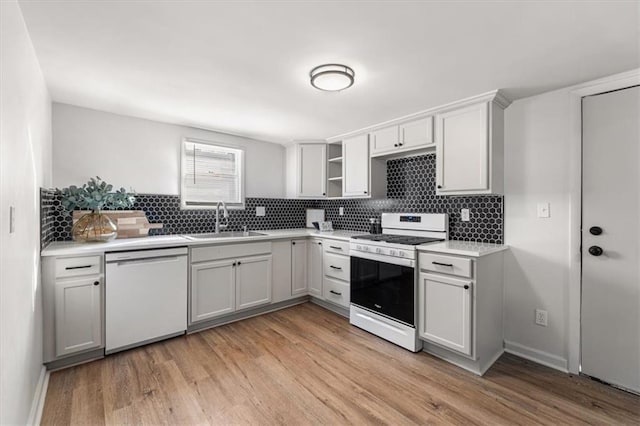 kitchen featuring a sink, light countertops, light wood-style floors, white appliances, and open shelves