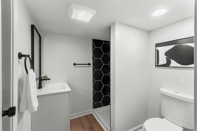 full bath featuring toilet, a stall shower, wood finished floors, baseboards, and vanity